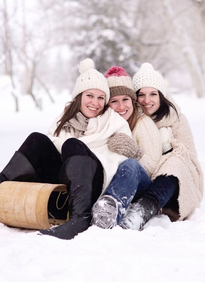 three women with scandi style beanies on a sled 