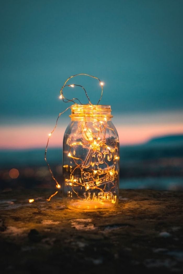 fairy lights in a big mason glass with a sunset in the background 