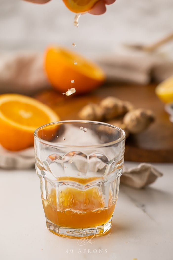 Orange juice being squeezed into an immune booster shot recipe glass