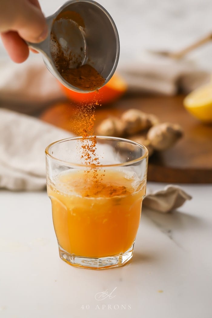 Spices being poured into a glass of immune booster shot
