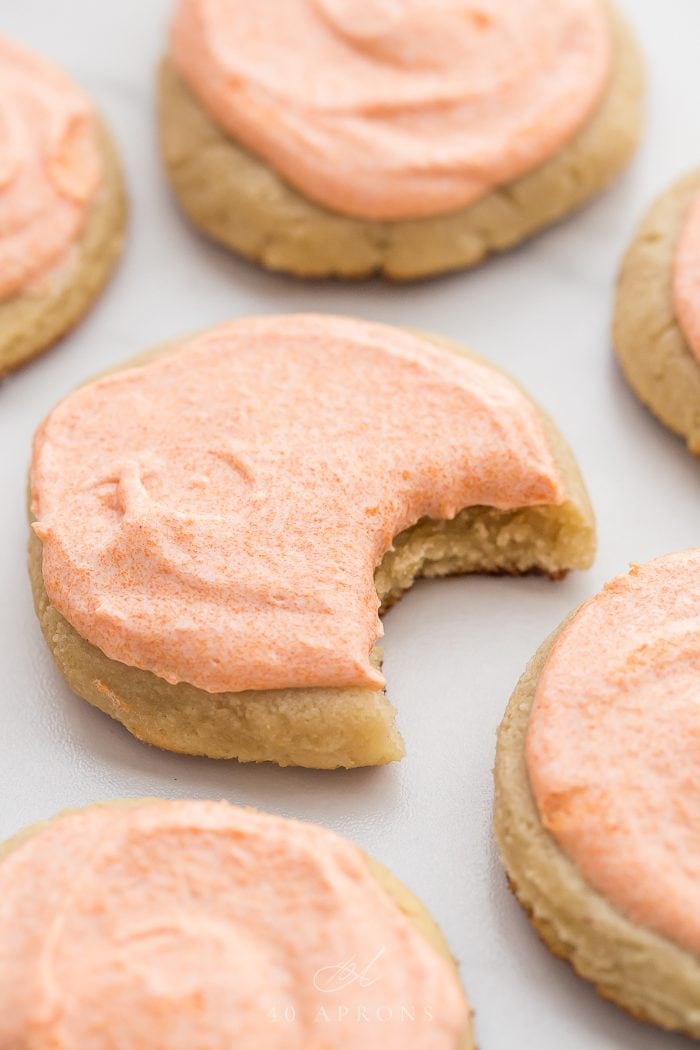 A pink frosted cookie with a bite taken out