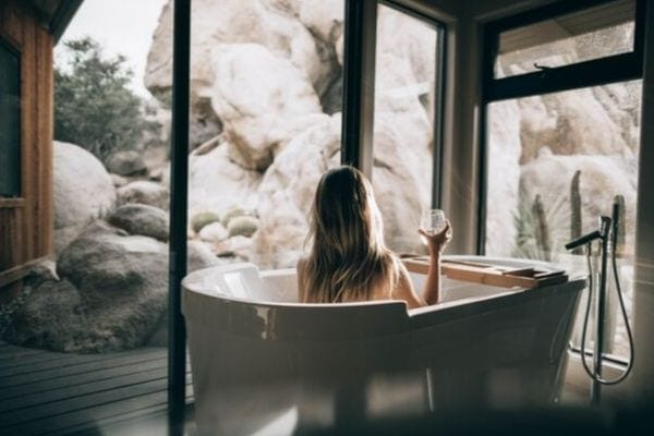 a woman sitting in a bath tub with a wine glass in hand