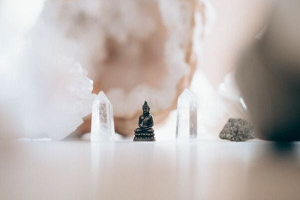 a small brass buddha between two crystals 