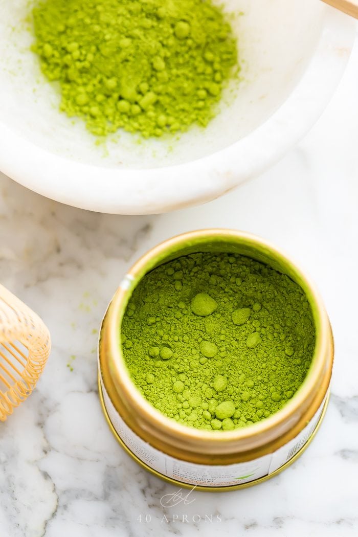 Tin of matcha with bowl of matcha to the back
