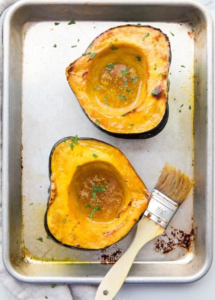 overhead shot of acorn squash on baking sheet basted with avocado oil.