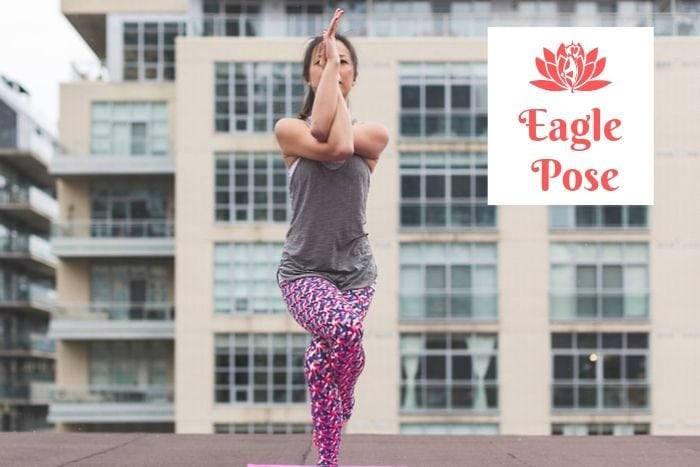 a woman holding the eagle yoga position in front of an apartment building