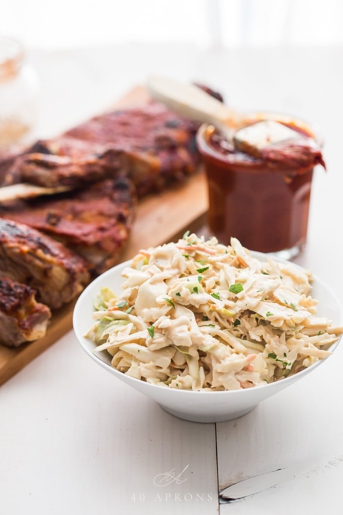 Healthy coleslaw in a white bowl infront of some ribs