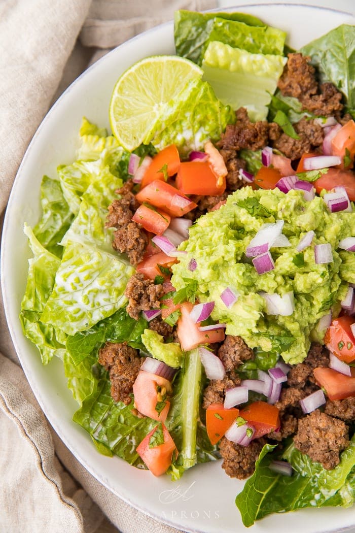 Heathy taco salad topped with guacamole, ground beef and red onions