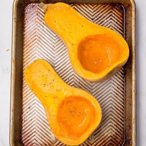 Butternut squash in half on a baking sheet