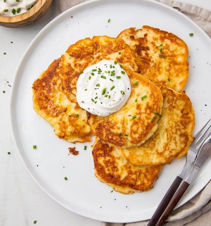 Leftover mashed potato pancakes on a white plate with a knife and fork