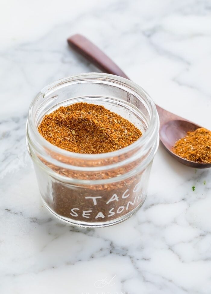 taco seasoning in a glass jar on a marble surface