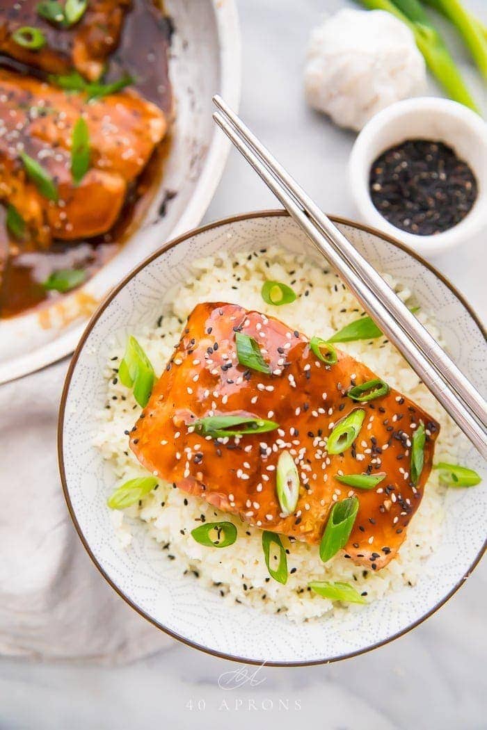 Whole30 teriyaki salmon over cauliflower rice in a bowl with chopsticks