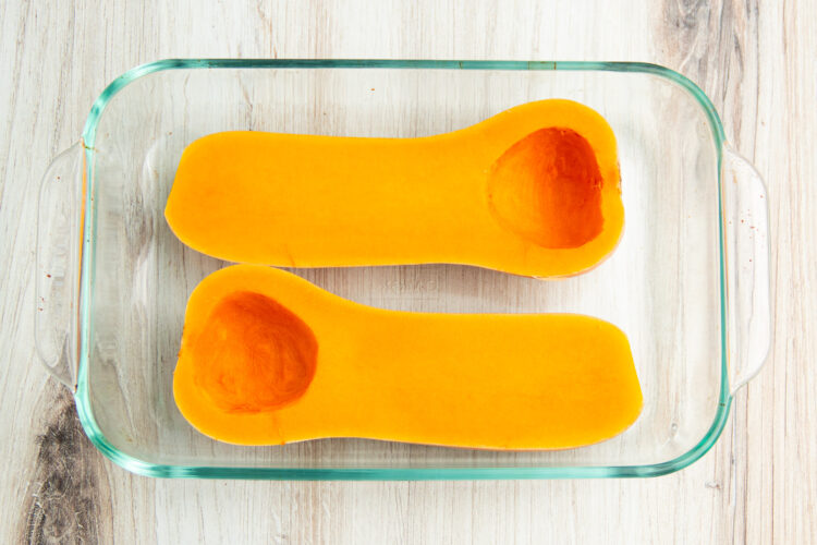 Butternut squash halves cut-side up in microwave-safe glass dish.