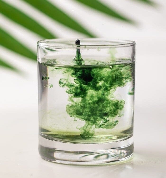 Liquid chlorophyll being dropped into a glass of water