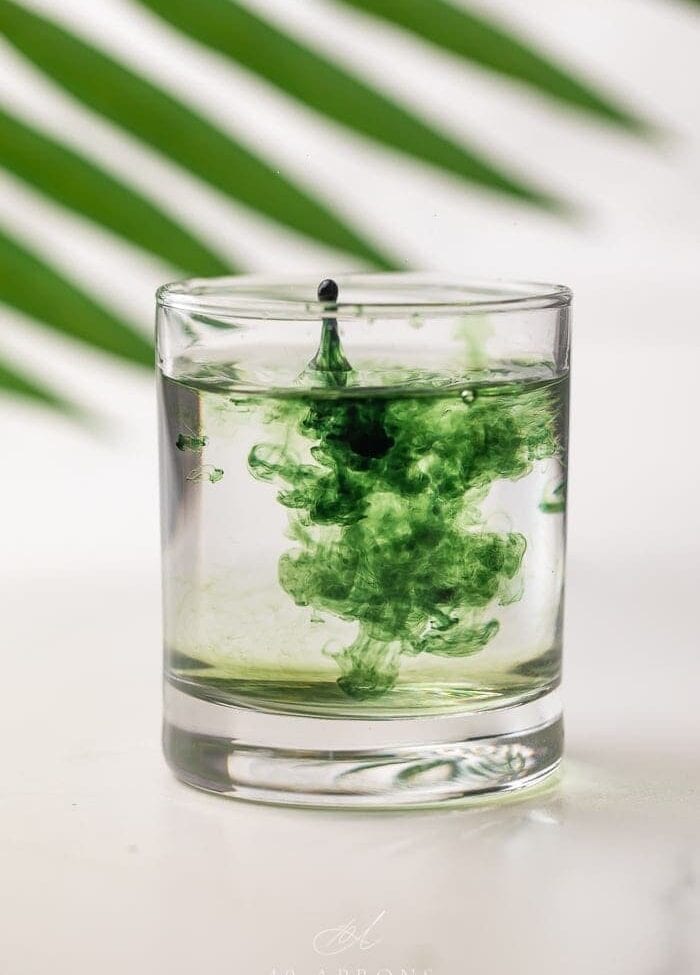 Liquid chlorophyll being dropped into a glass of water