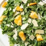 Kale caesar salad on a white plate with croutons