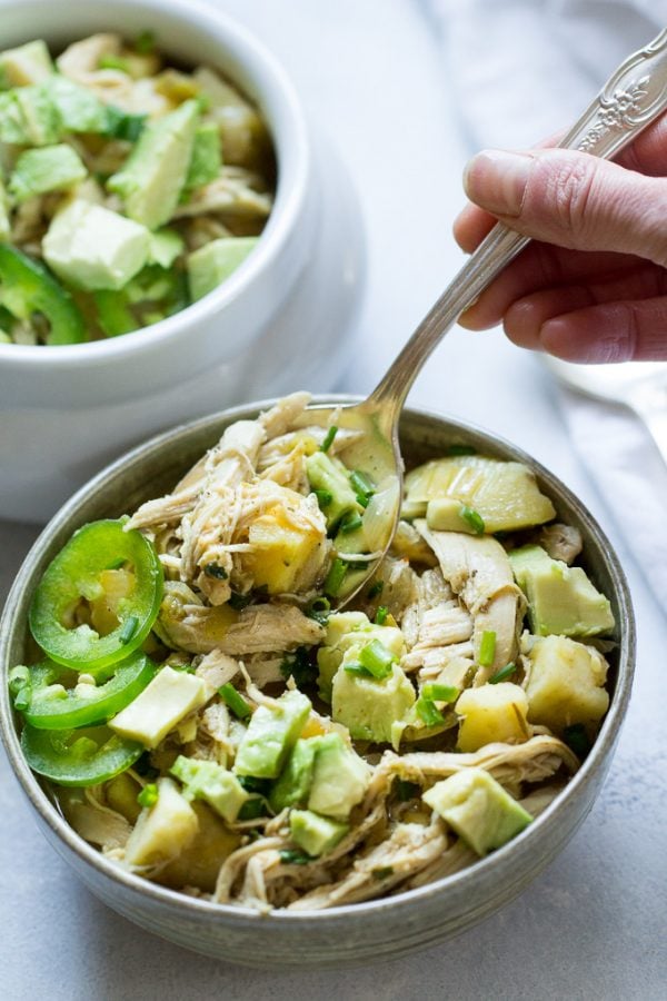 Slow cooker white chili being eaten with a spoon