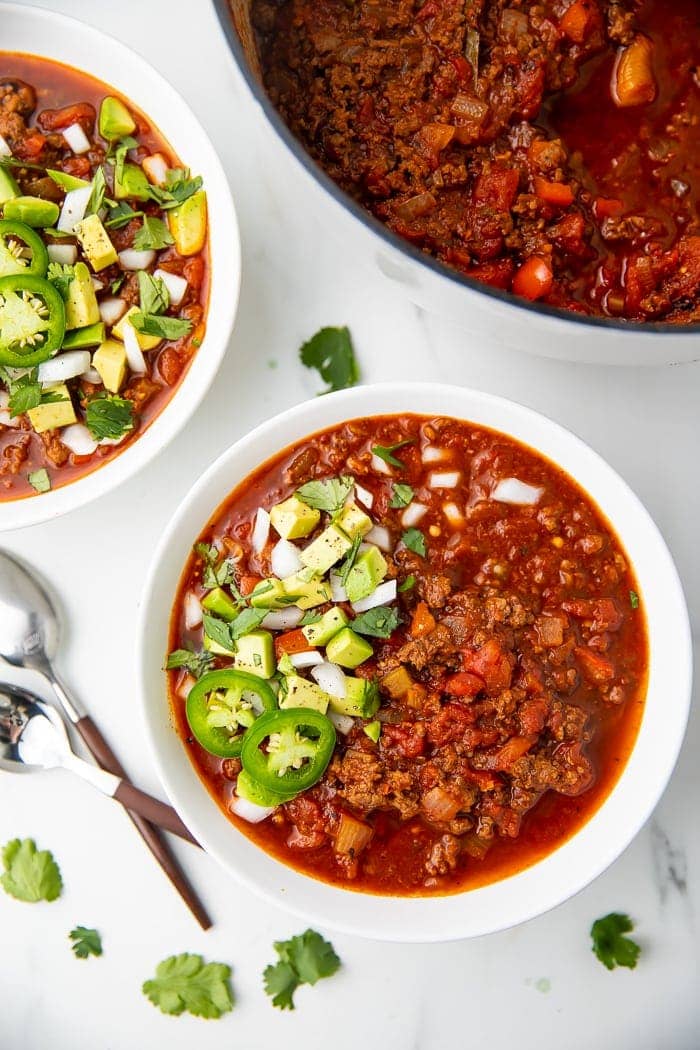 Bowl of Whole30 chili garnished with jalapenos, onions, and avocados
