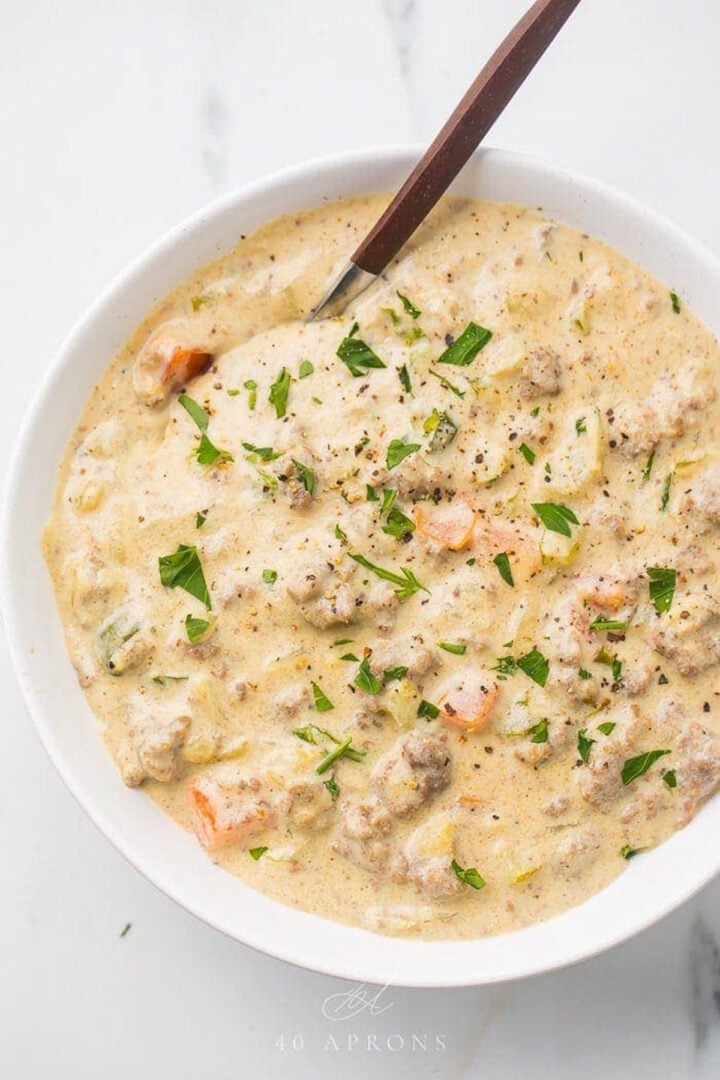 Cheeseburger soup in a white bowl with a spoon.