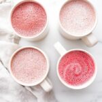 Four pink lattes in white mugs