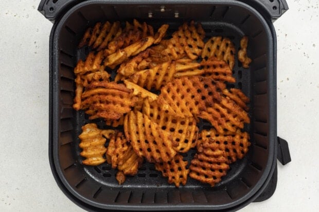 Cooked frozen waffle fries in air fryer basket