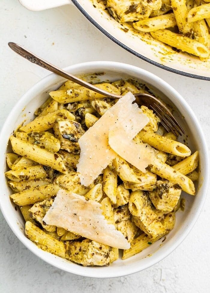 One-pot chicken pesto pasta in a bowl topped with Parmesan cheese