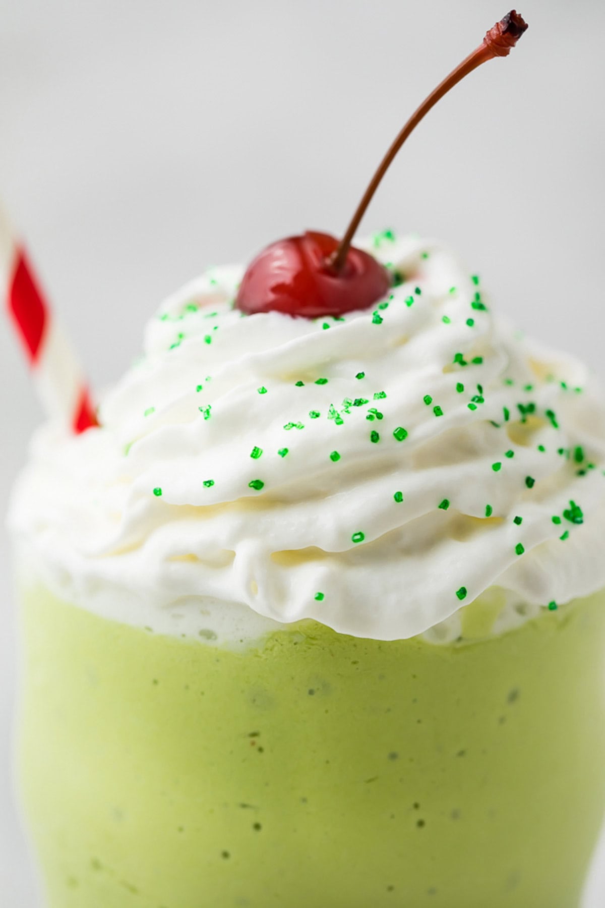 Close-up on a dairy-free shamrock shake topped with whipped cream and a cherry.