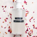 Homemade hand sanitizer recipe in bottle on dried rose petals