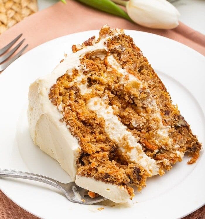 Slice of paleo carrot cake on a white plate with a fork