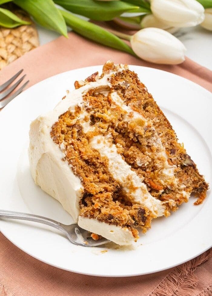 Slice of paleo carrot cake on a white plate with a fork