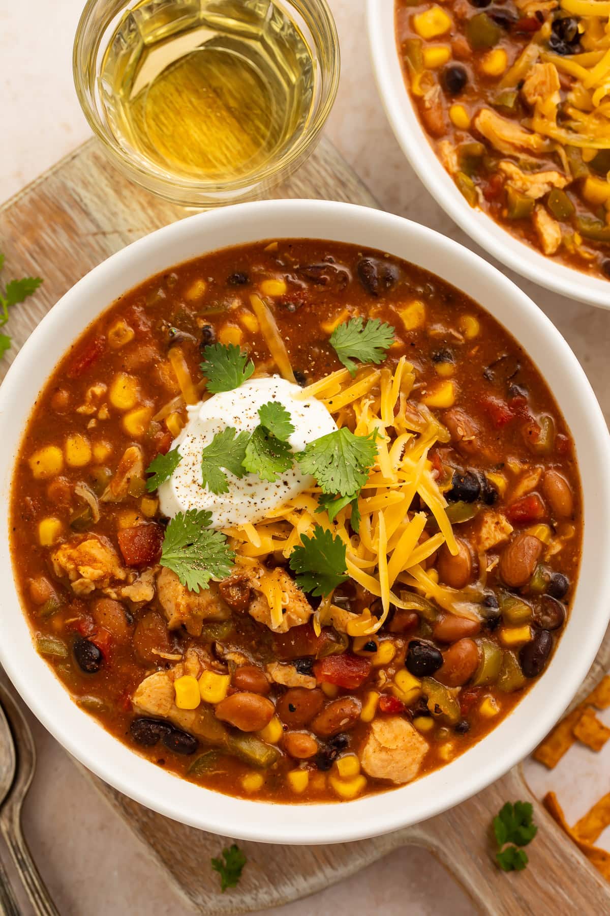 Bowl of homemade taco soup with colorful beans, corn, and garnishes on wooden cutting board