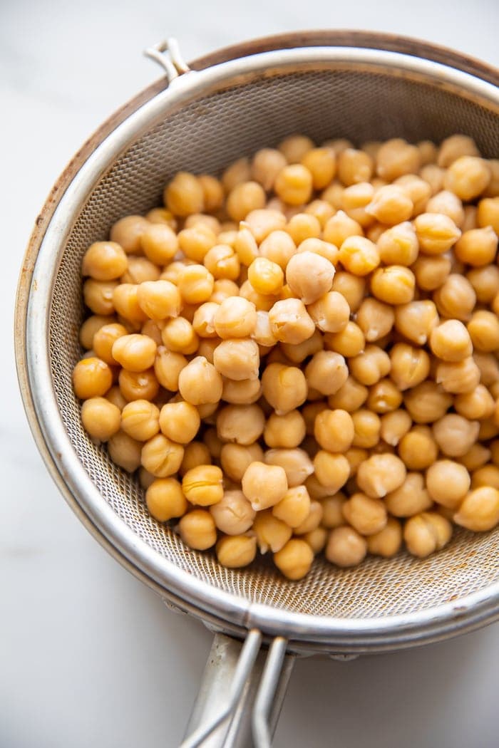 Chickpeas strained in a colander over a saucepan