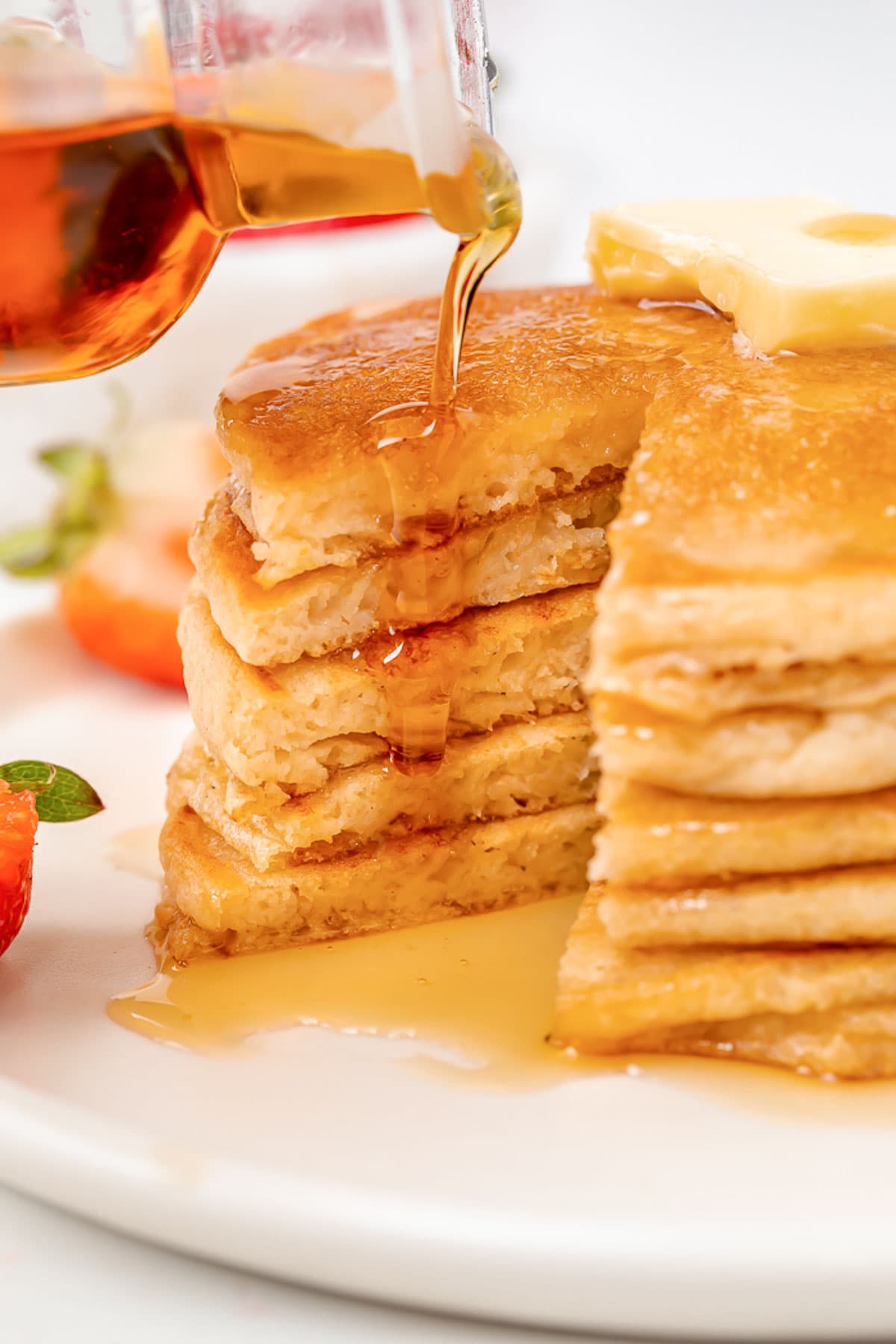 Syrup poured over a stack of gluten-free pancakes after a wedge has been cut out.