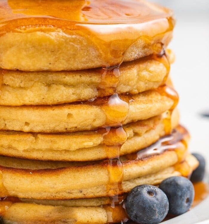 Stack of paleo pancakes with a pat of butter and syrup with blueberries to the side