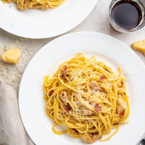 Chicken carbonara on a plate with a glass of red wine