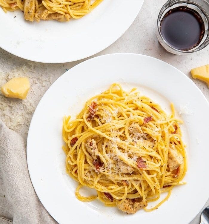 Chicken carbonara on a plate with a glass of red wine