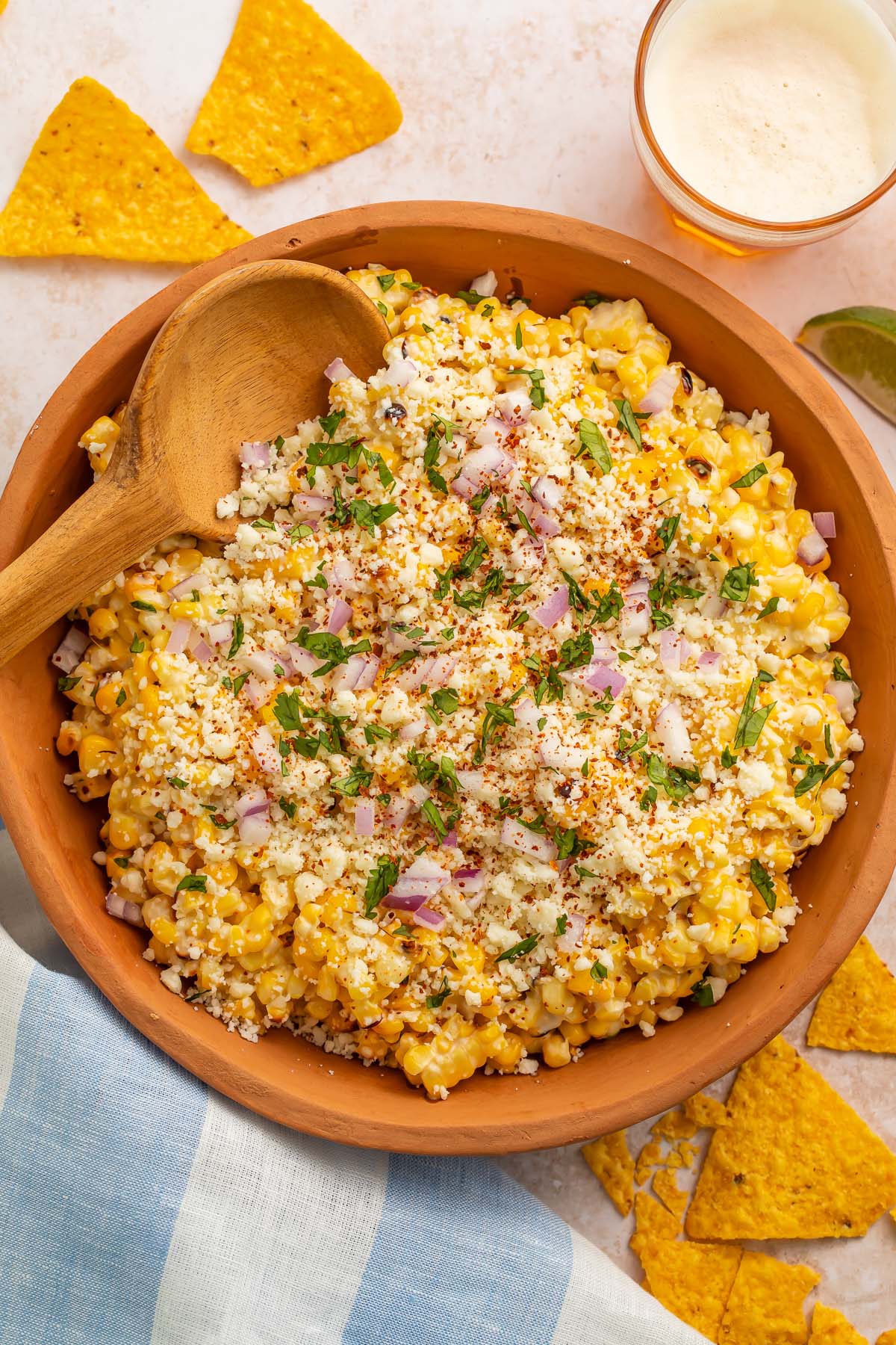 Top-down photo of a large wooden bowl holding a Mexican street corn salad.