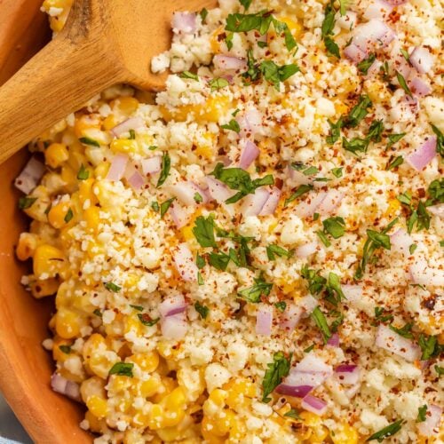 Close-up photo of a large wooden bowl holding a Mexican street corn salad.