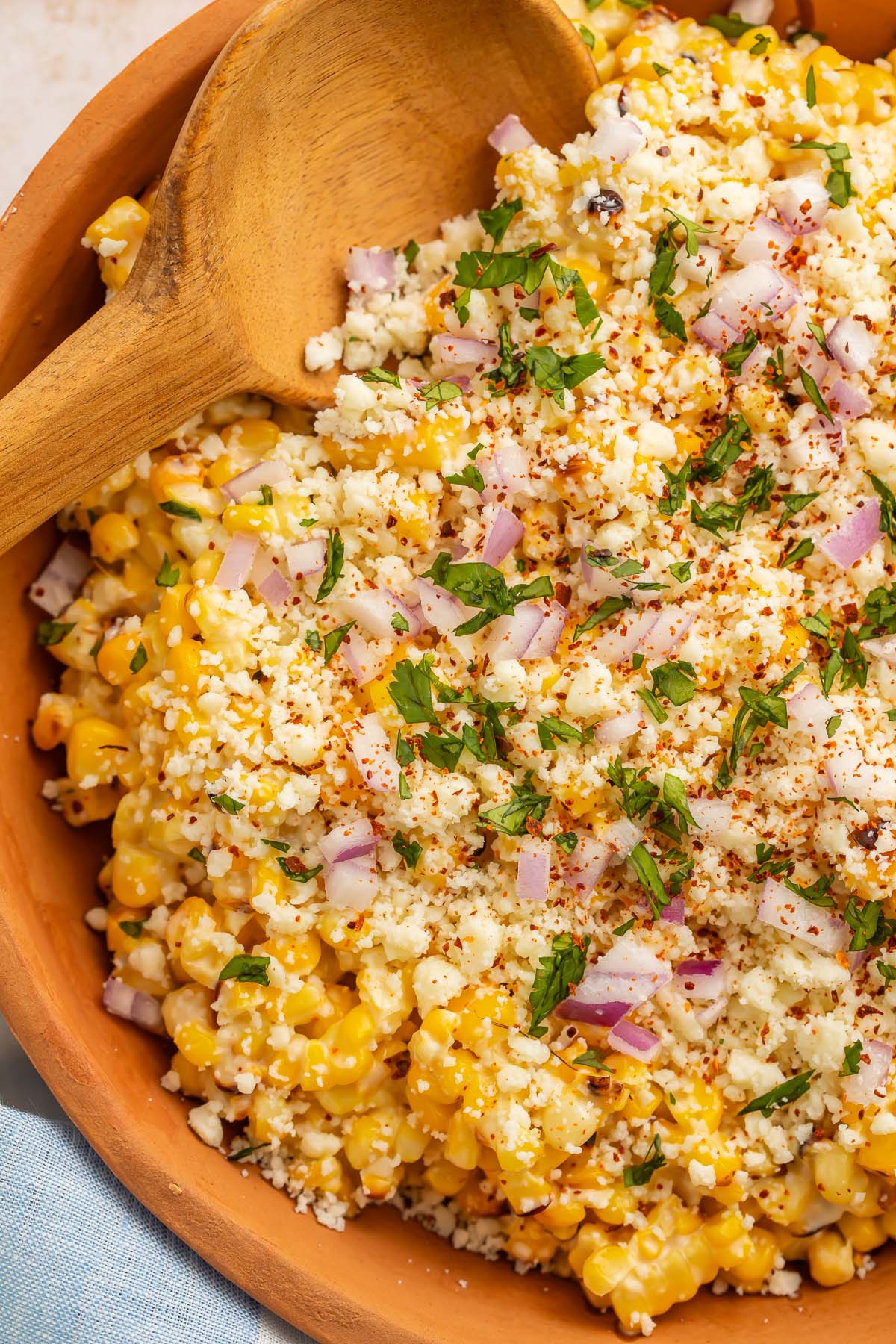 Close-up photo of a large wooden bowl holding a Mexican street corn salad.