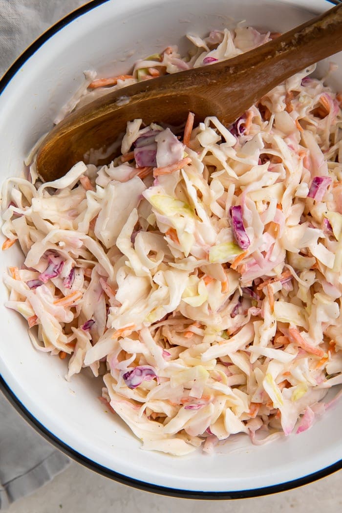 Keto coleslaw in a bowl with a wooden spoon
