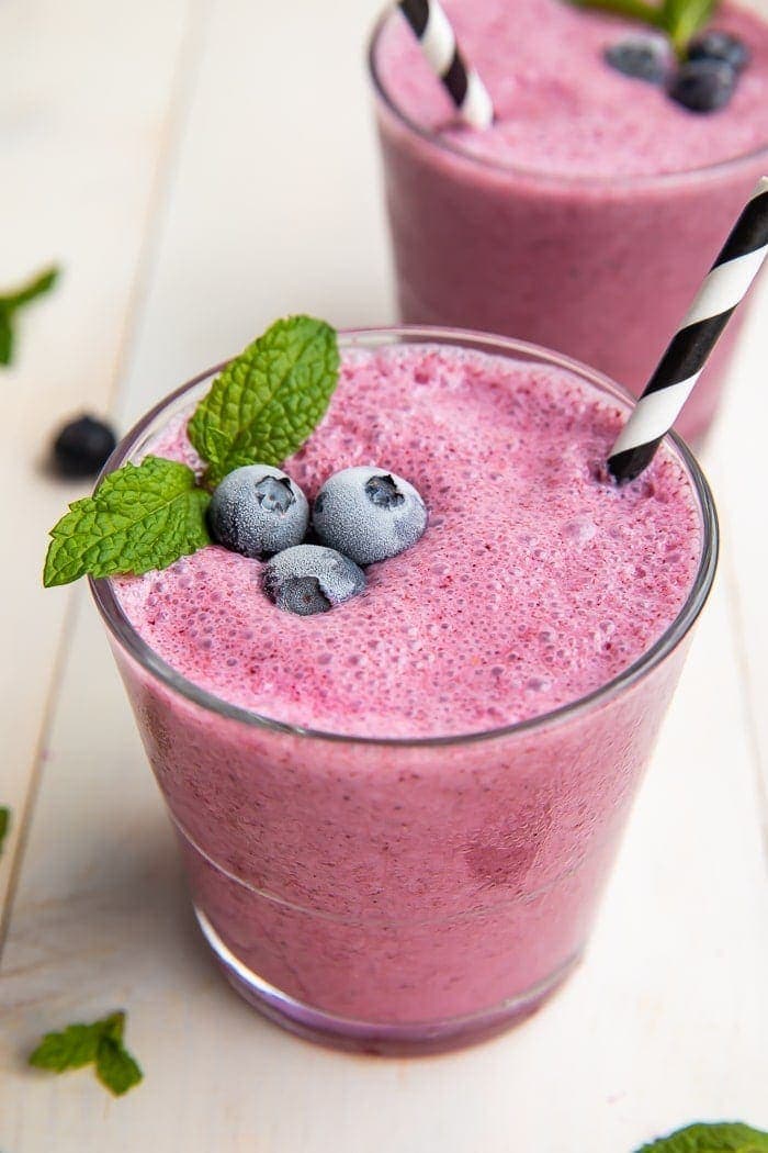 Blueberry smoothie in a glass with a straw