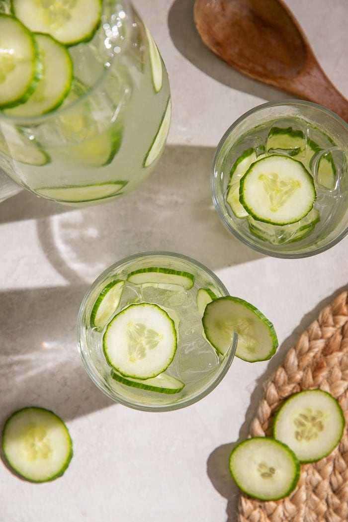 Overhead shot of two glasses and a pitcher of cucumber water