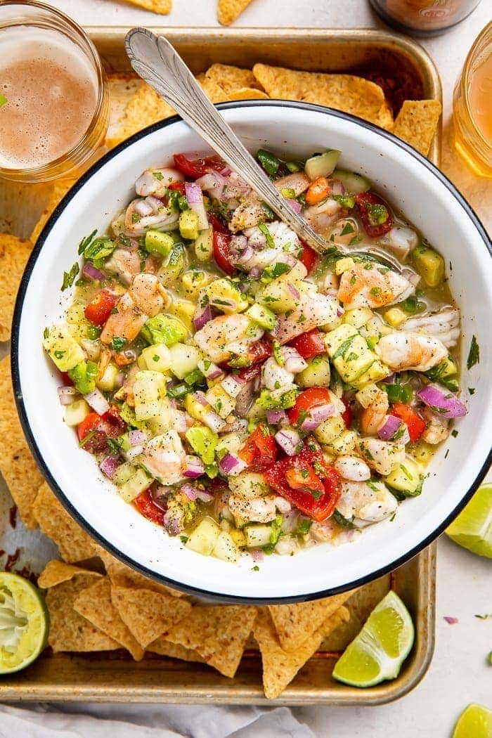 Shrimp ceviche in a bowl with chips and lime wedges