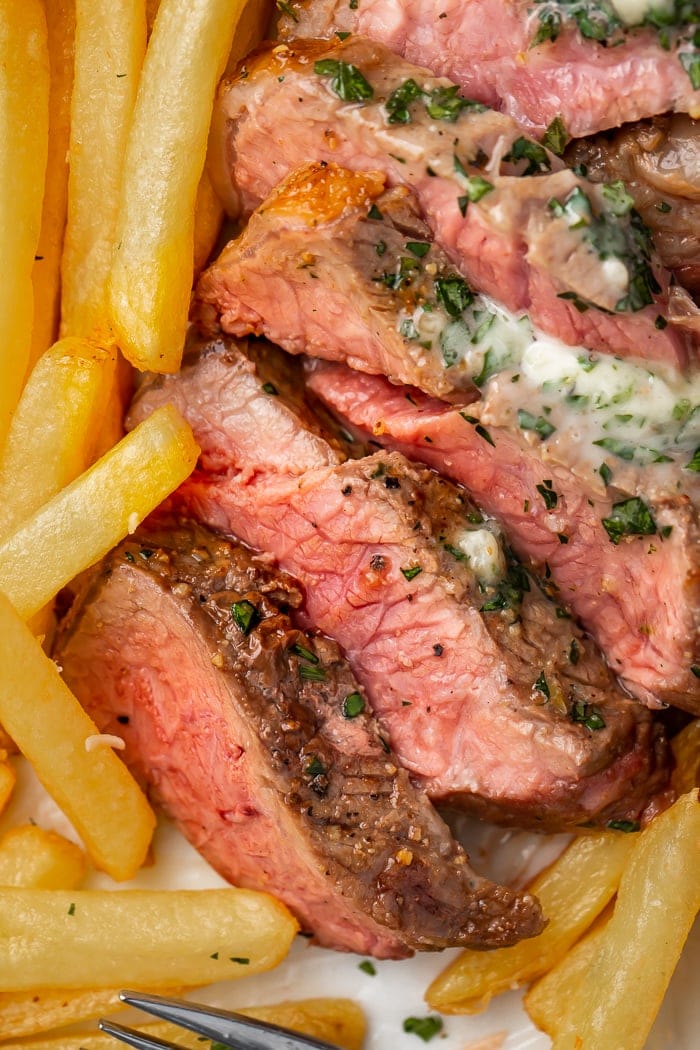 Close-up of air fryer steak cut into slices next to french fries