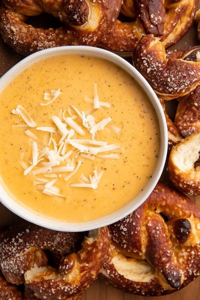 Bowl of beer cheese dip surrounded by pretzels