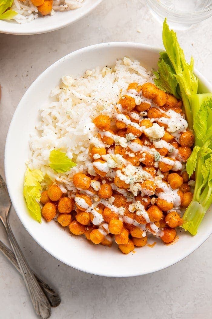 Chickpeas with buffalo sauce and ranch on a bed of white rice and celery tops