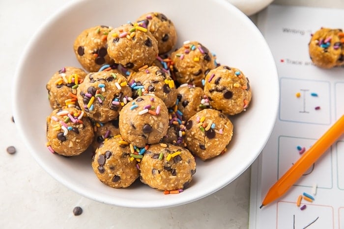 peanut butter and chocolate chip energy balls in a white bowl with sprinkes