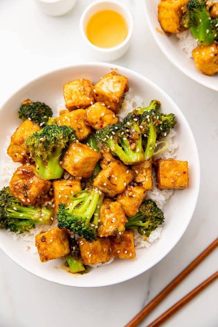Tofu and broccoli on a plate with white rice and sesame seeds