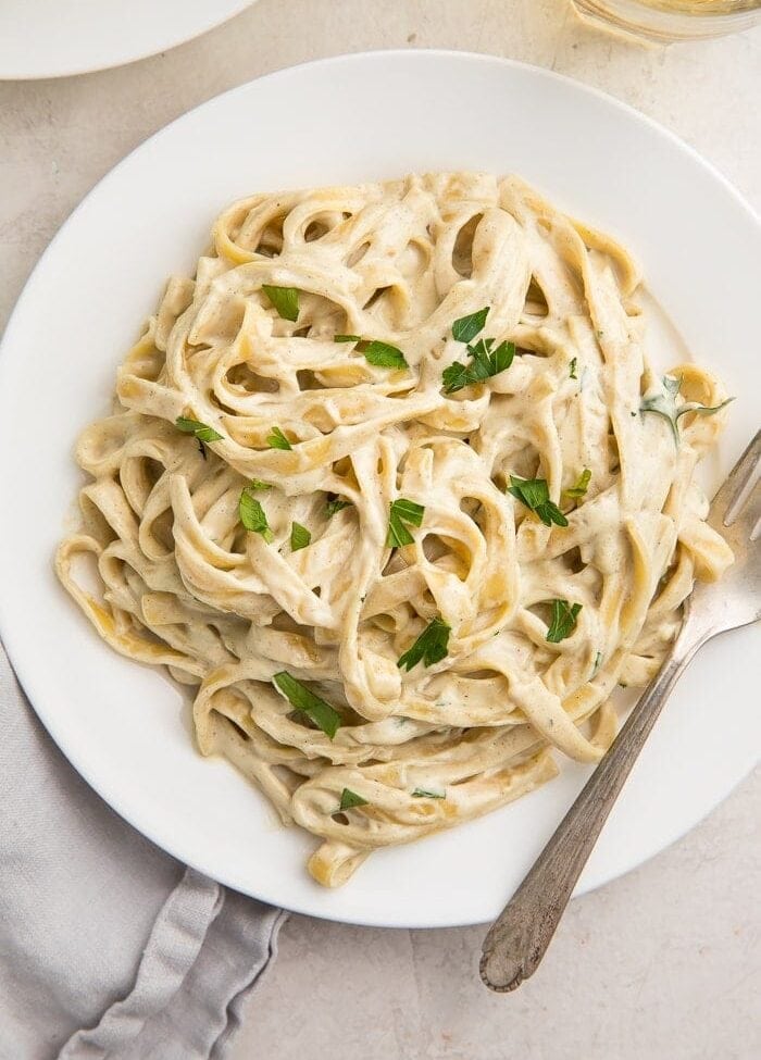 White plate of pasta with vegan alfredo sauce