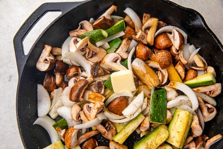 Sauteed fresh veggies in a large cast-iron skillet on a stove.